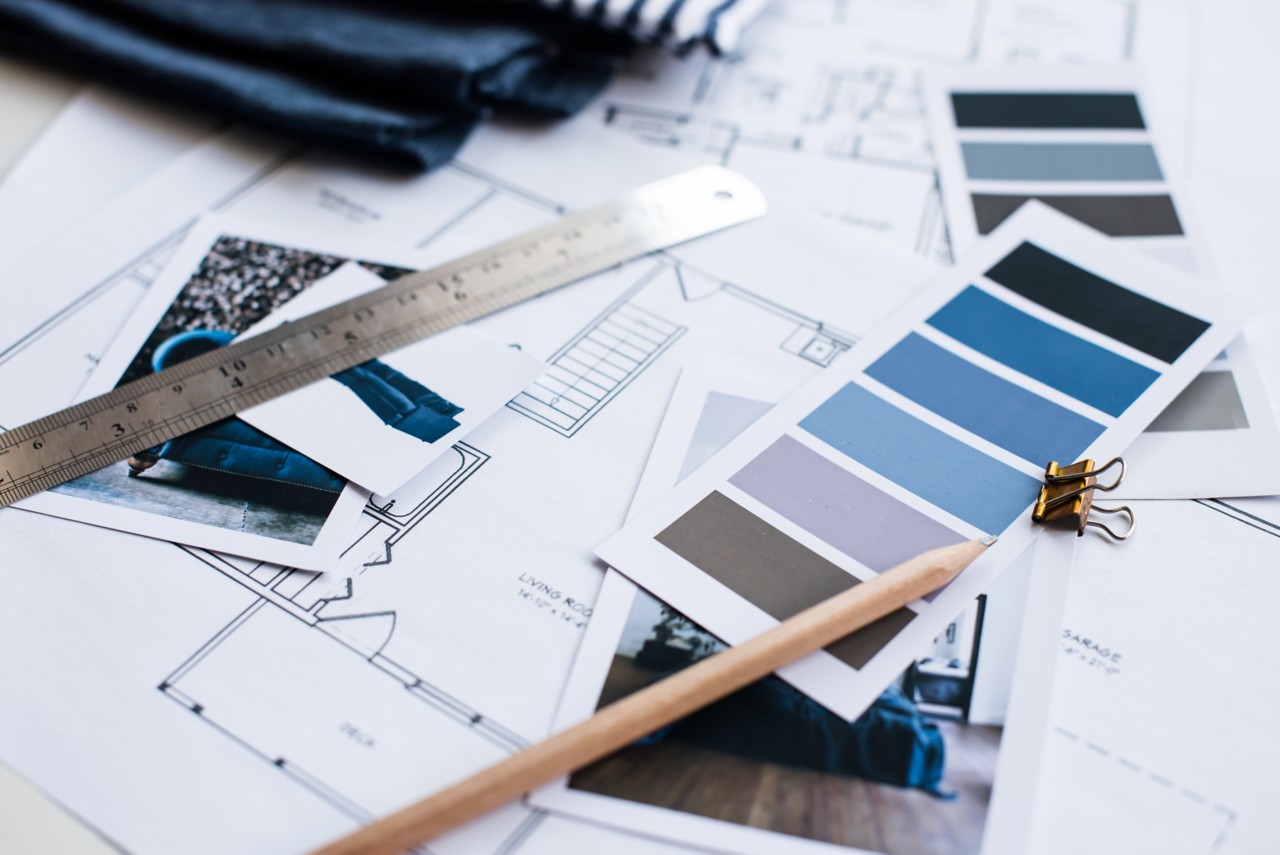 Interior designers working table - an architectural plan of the house, a color palette, furniture and fabric samples in blue color. Drawings and plans for house decoration.