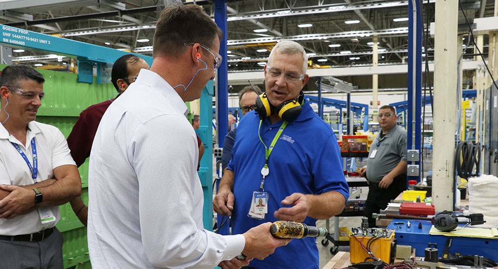 Governor Stitt talking with a working in a factory