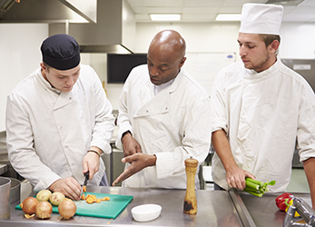 culinarystudents01 Teacher Helping Students Training To Work In Catering Chopping Vegetables