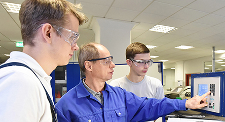 workplacetour01 young apprentices in technical vocational training are taught by older trainers on a cnc lathes machine