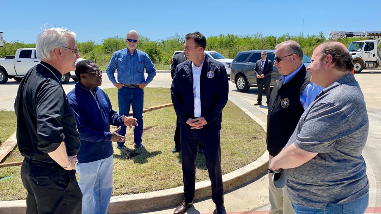 Governor Stitt, outdoors, talks with people about public transit agencies