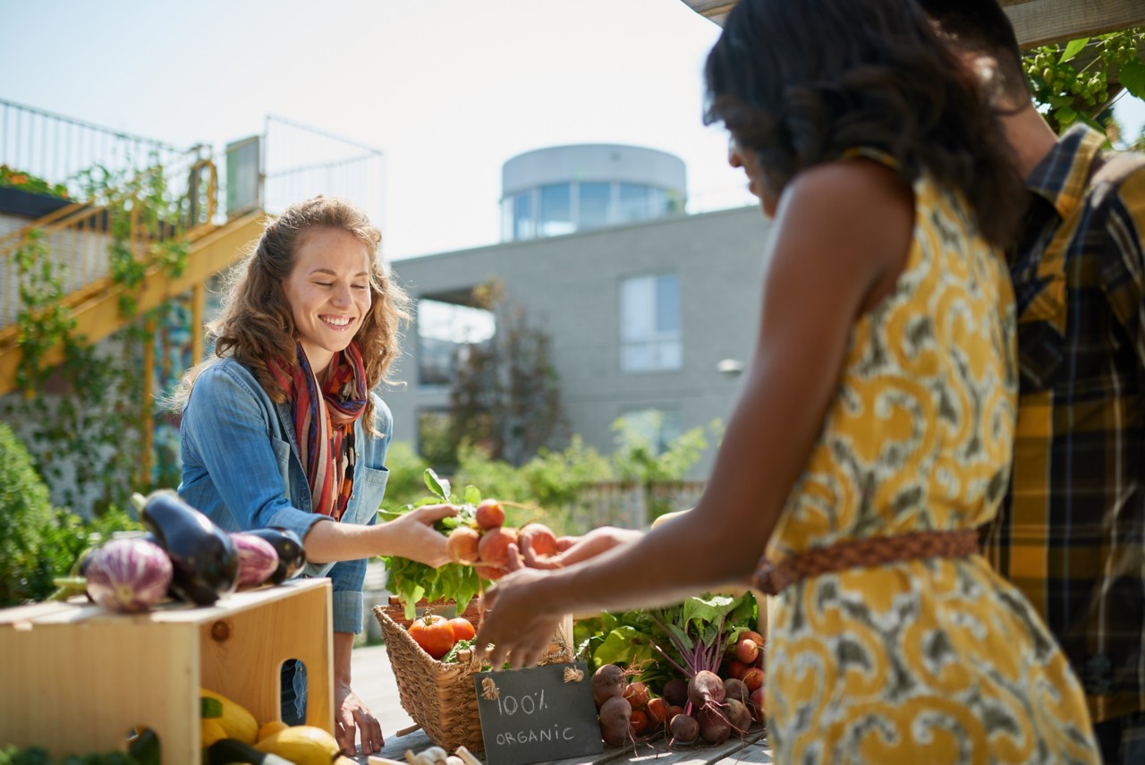 People examine produce at an outdoor market.