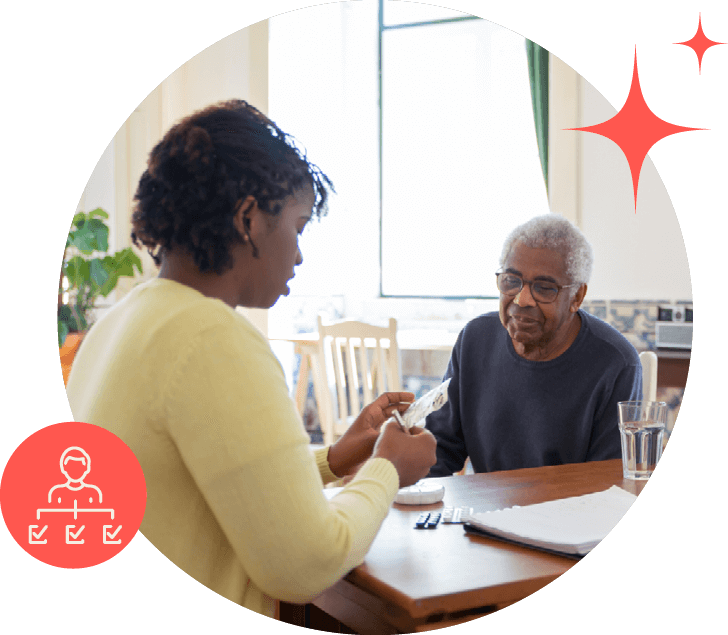 Young Black woman and older Black man sitting at a table. The woman is putting pills into a pill box.