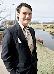 Skyler Riggle wearing a dark suit with a patterned tie in shades of brown.