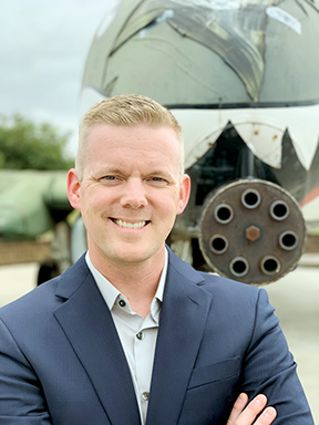 Head and shoulders shot of Justin Cockroft with the front of an airplane behind him.