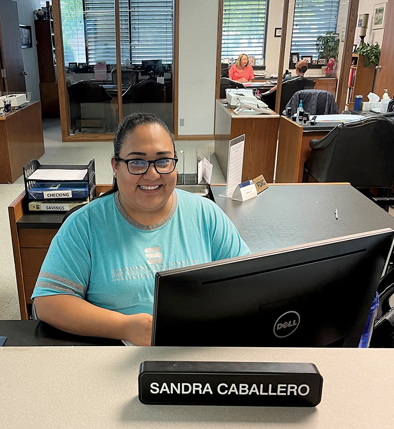 Sandra Caballero sits at a desk behind a nameplate with her name on it.