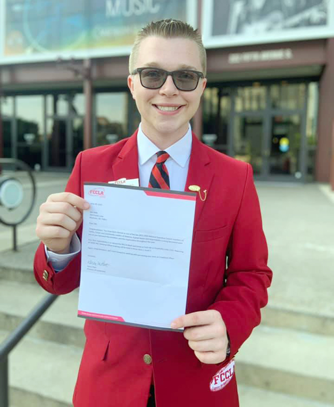 Oklahoma FCCLA member Zeb Kelly, Morrison Public Schools, wears his red FCCLA blazer and holds up his national officer election letter.