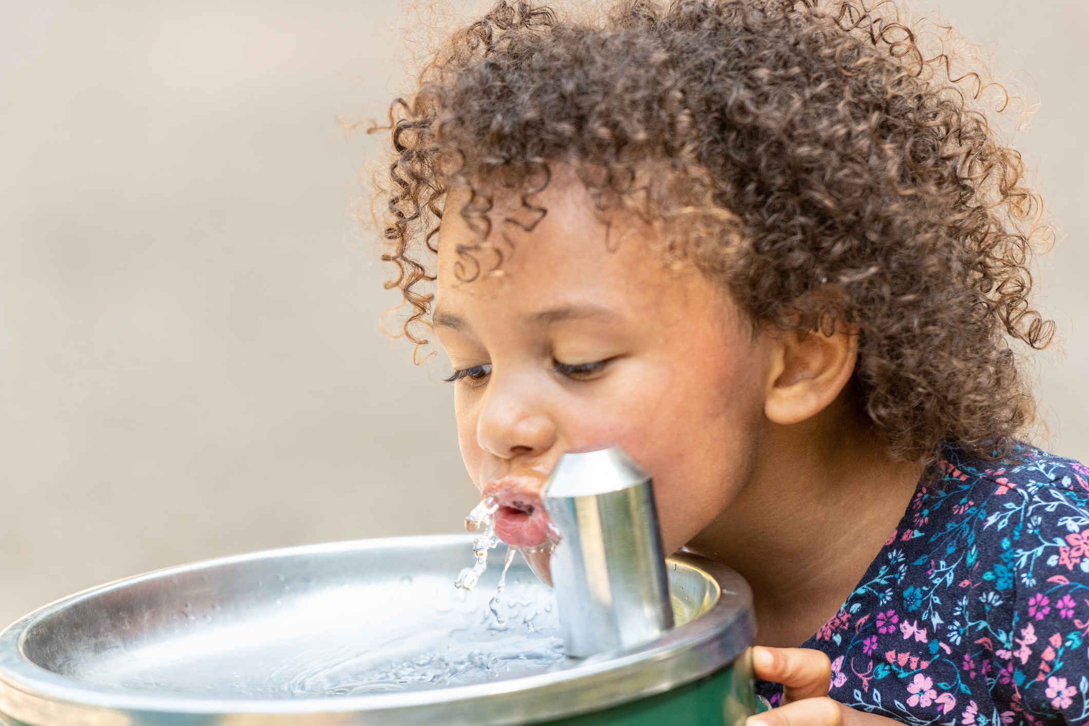 Girl drinking water out of water fountain.