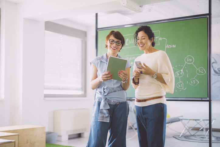 Two teachers looking over notebook in classroom setting.