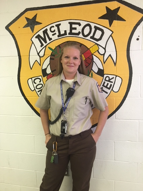 Howard McLeod Correctional Center employee Brandi Graham-Martinez standing in front of the McLeod badge.