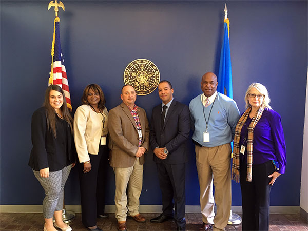 Xavier McElrath-Bey with Acting Region II Director Millicent Newton-Embry, Joseph Harp Correctional Center Warden Carl Bear, JHCC Deputy Warden Jenny Dillon, Lexington Assessment and Reception Center Warden Jeorld Braggs, and Public Information Officer Sarah Bildstein.