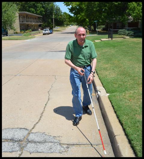 Hill walking up the street using his white cane