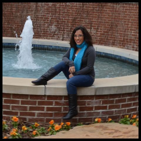 a woman sits on a water fountain edge