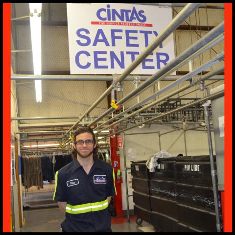 A man in a factory standing under a sign that reads Cintas Safety Center