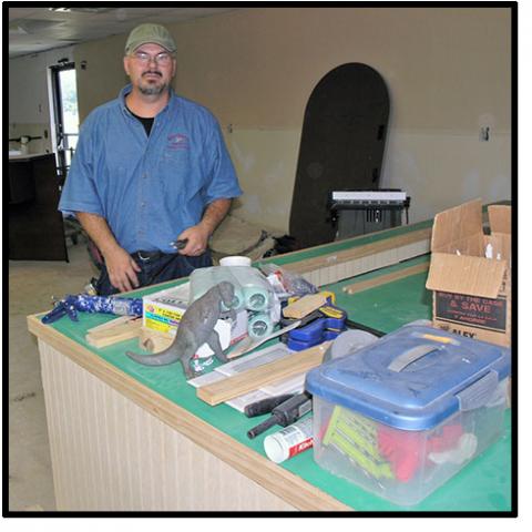 Kenneth Poore standing at construction site with lumber and tools on a table