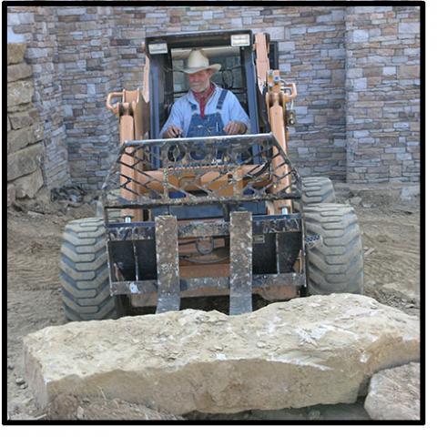 A man using a fork lift to move a large bolder