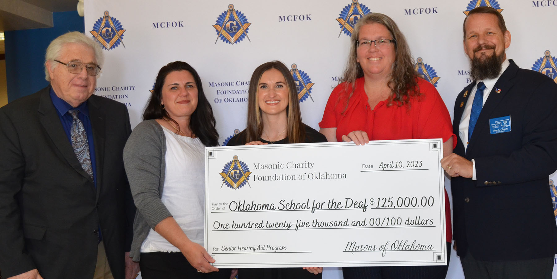 5 people hold a large 125,000 check to OK School for the Deaf from Masonic Foundation