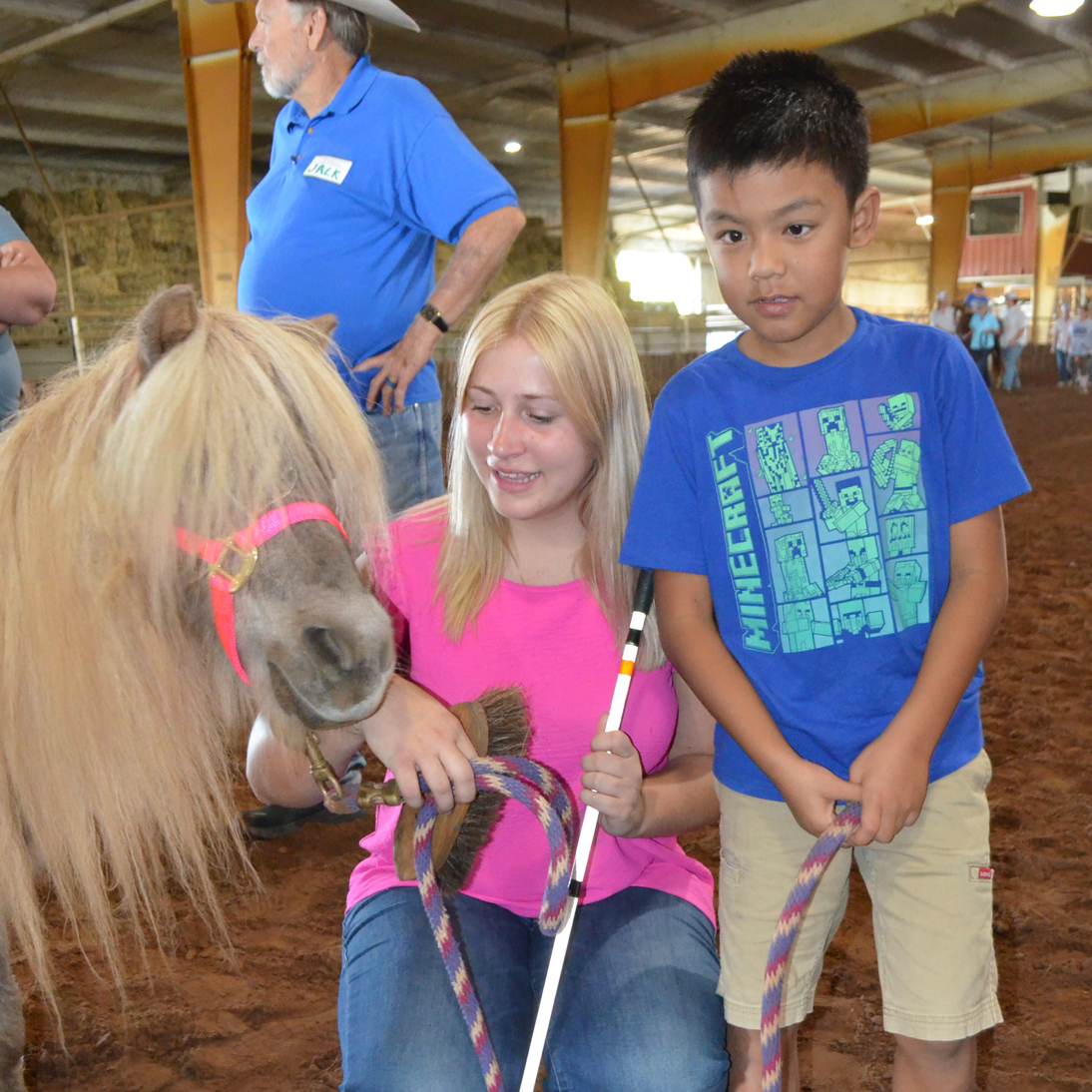 a volunteer and a student hold a pony by the lead.