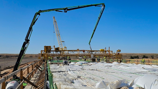 Workers lay more concrete via pump on the opposite side of curing concrete