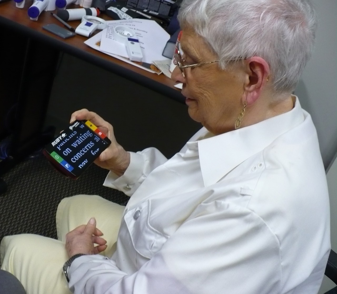 An older woman looking at a handheld device that magnifies text