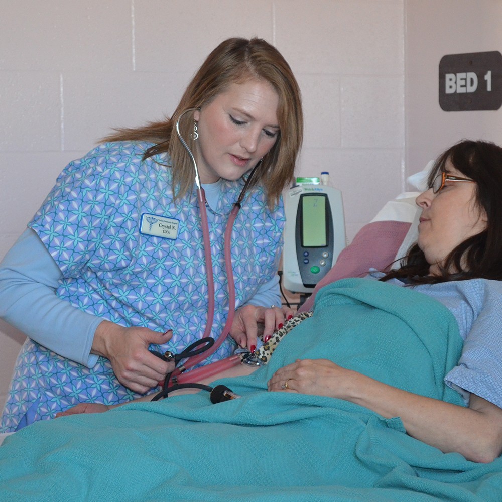 Nurse taking the blood pressure of a patient in a hospital bed.