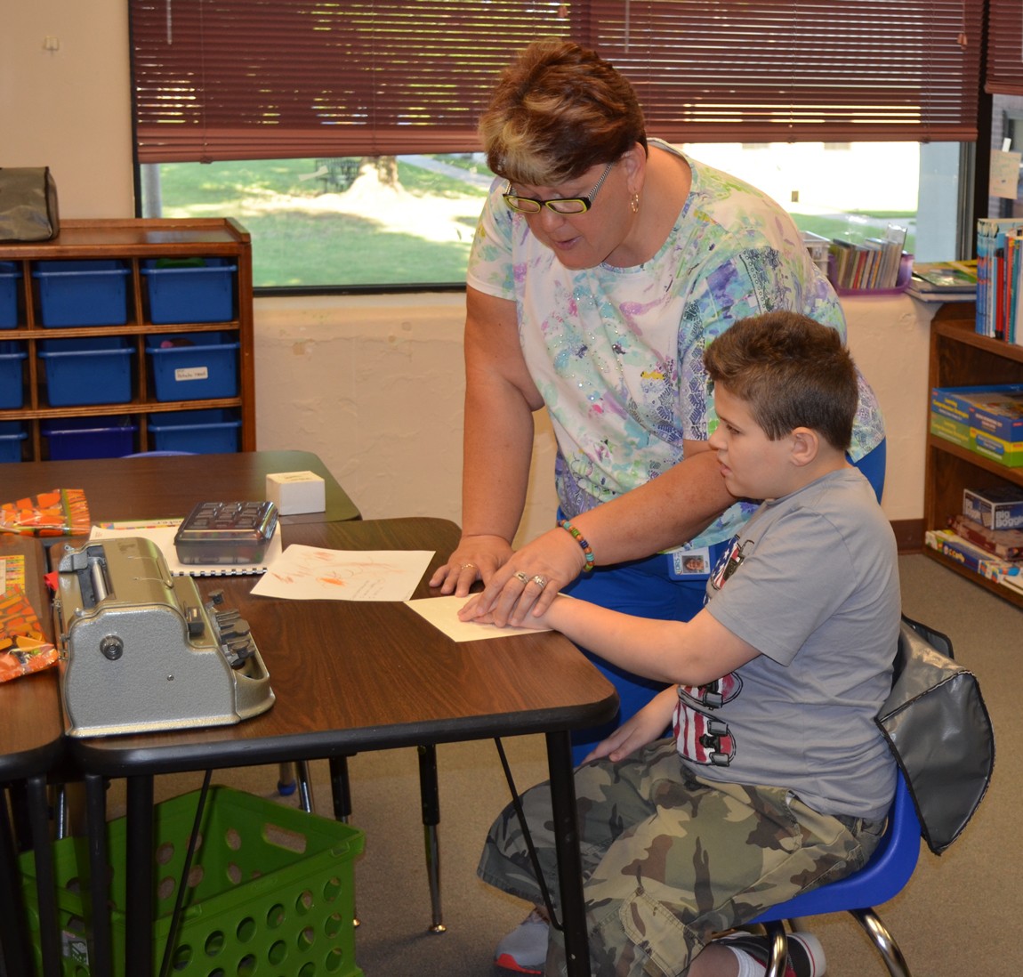 A teacher helps a student read braille