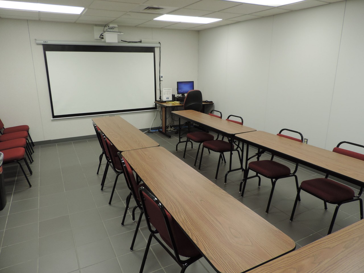 Conference or training room with available projector, white/smart board, and tables/chairs.