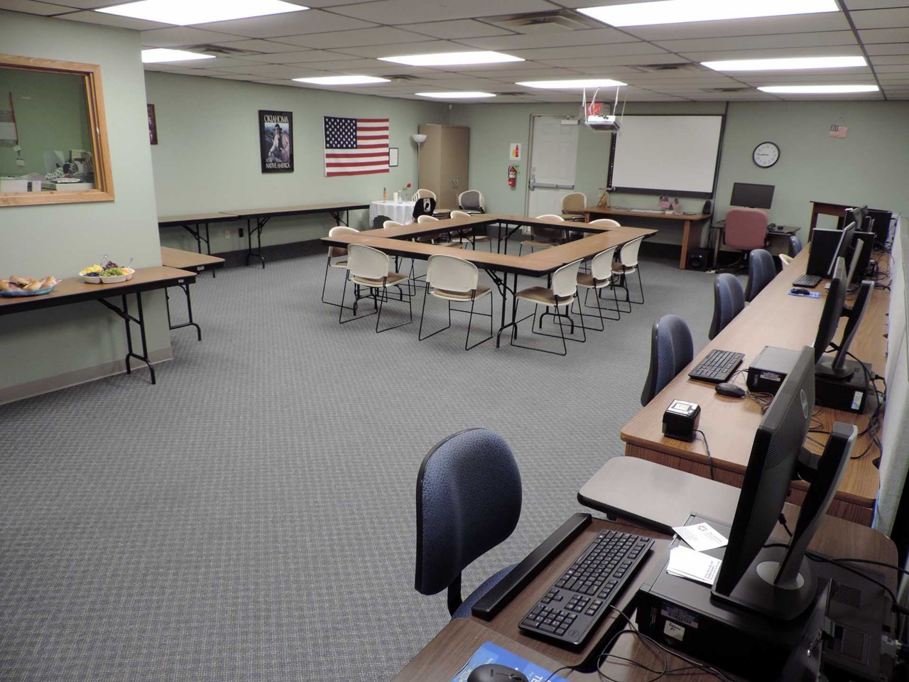 Conference or training room with available computers, projection screen, and table/chairs.          