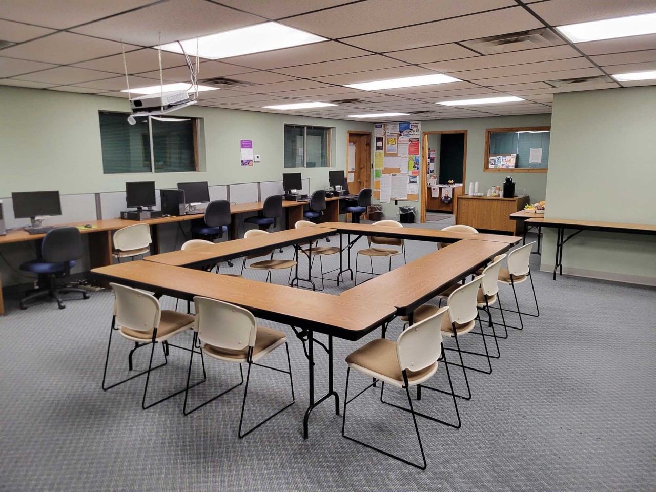 Conference or training room with available computers, projection screen, and table/chairs.