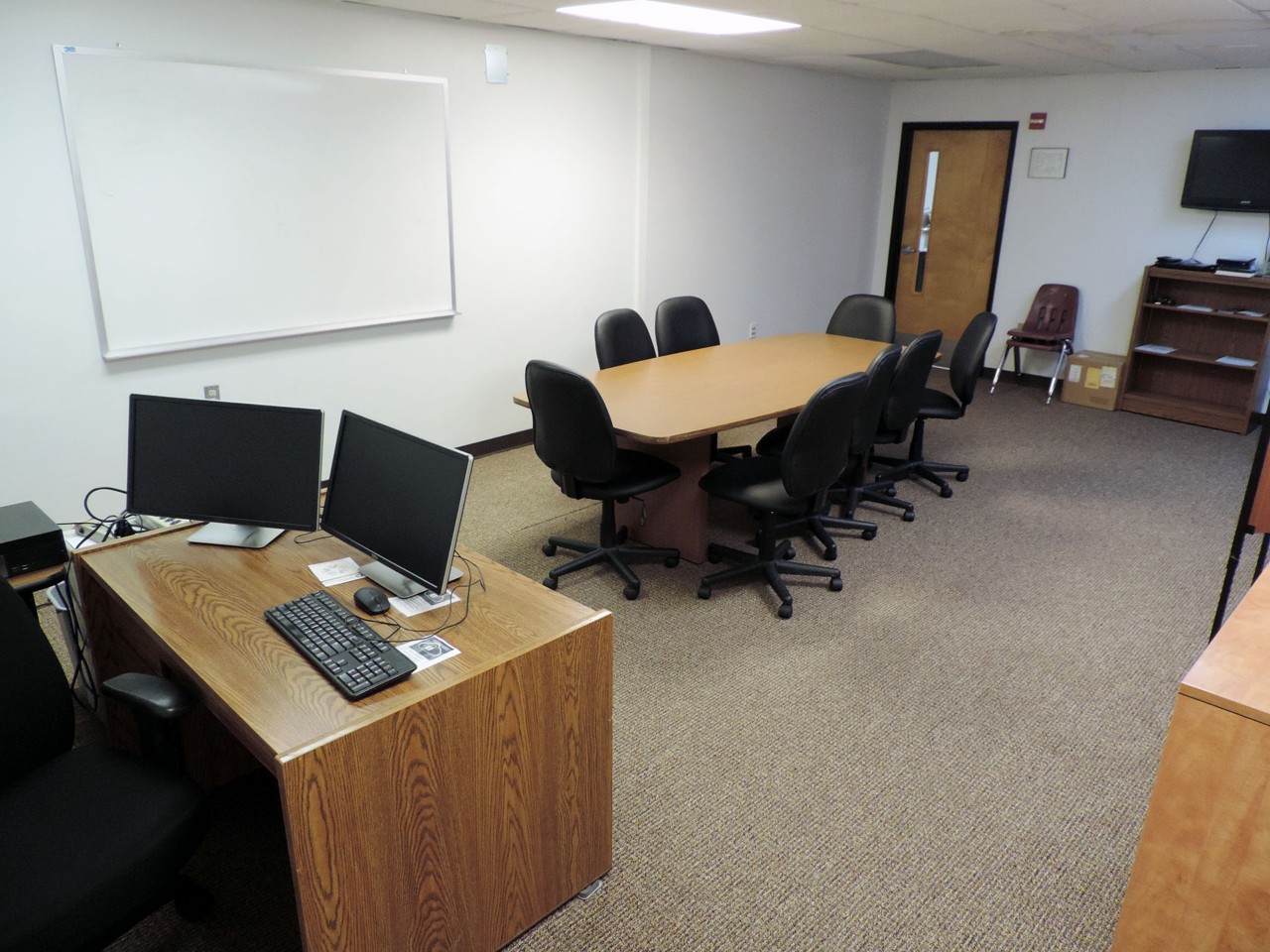 Interview room with available desk, table/chairs, computer, TV and white board.    