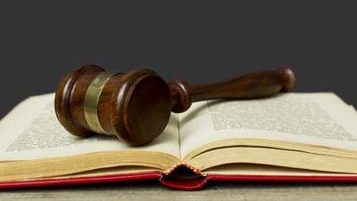 An open law book with a gavel on top.