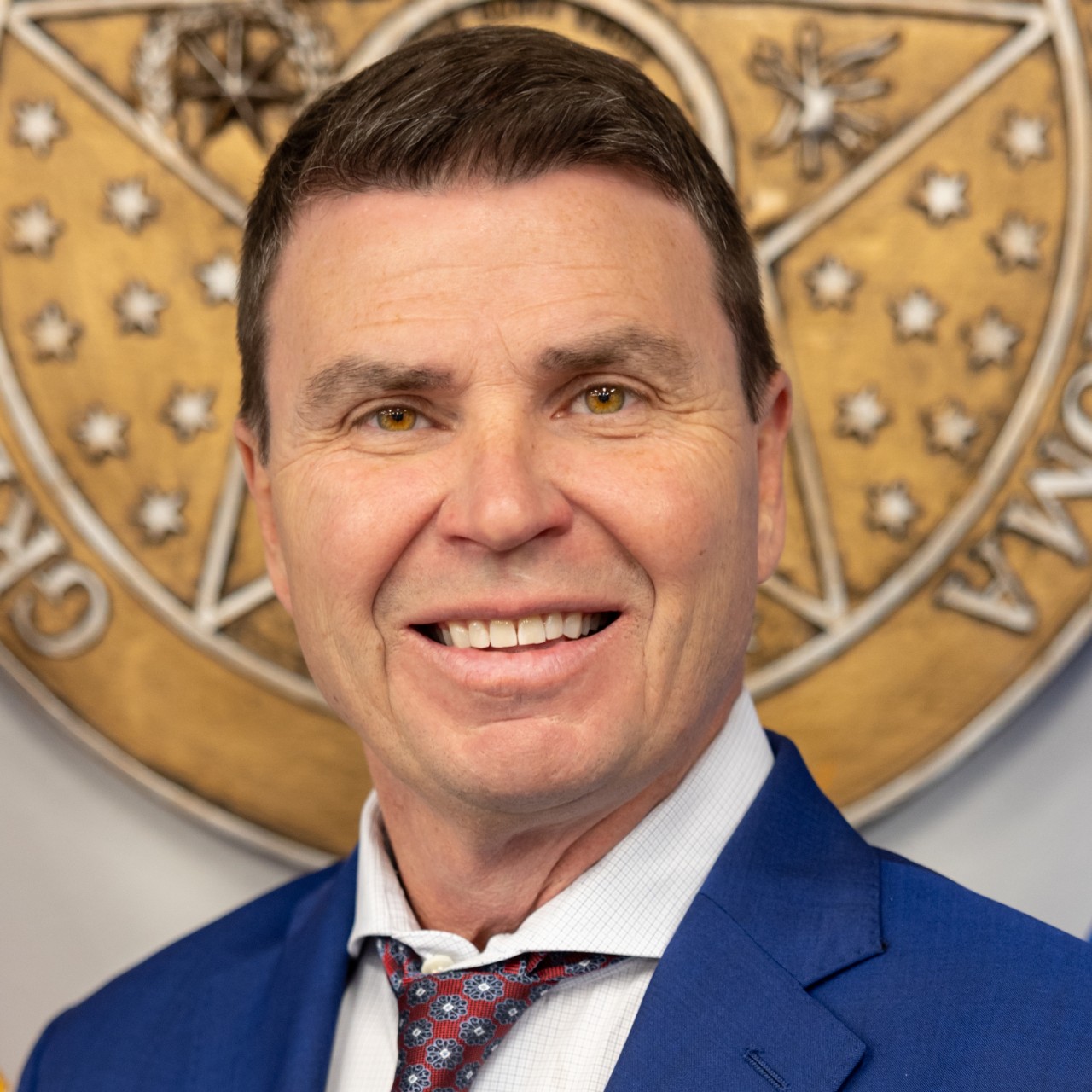 Image of Lindel Fields in front of Oklahoma Seal