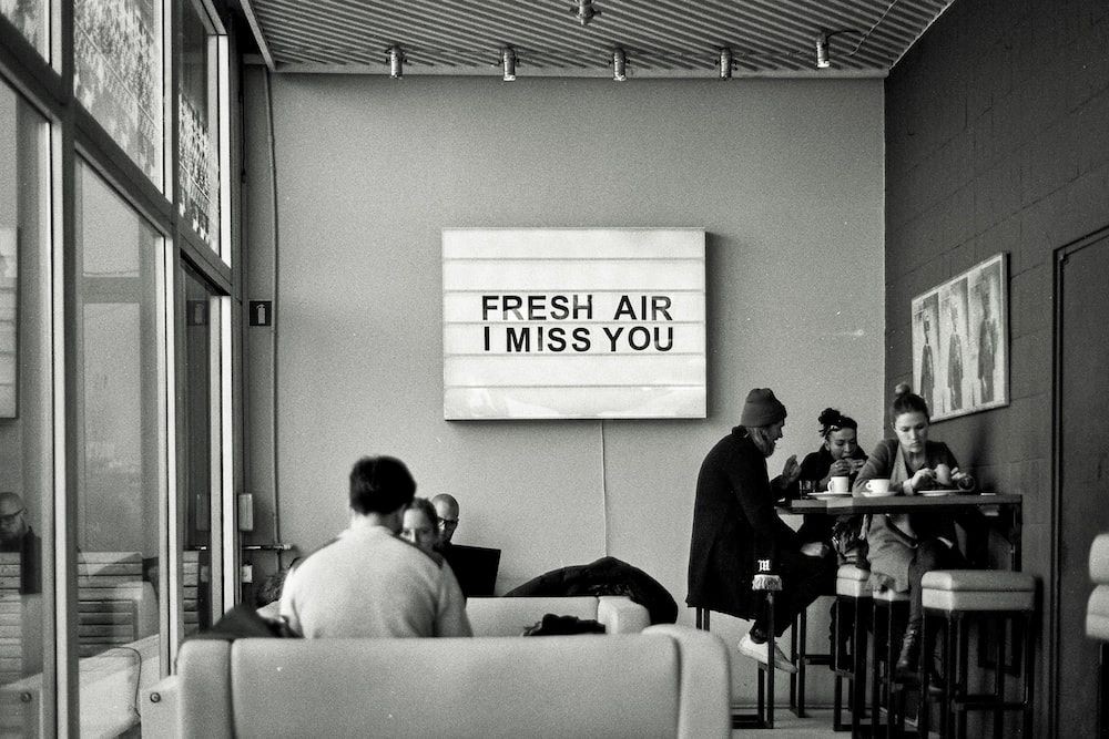A sign in a restaurant reads "Fresh Air I Miss You."