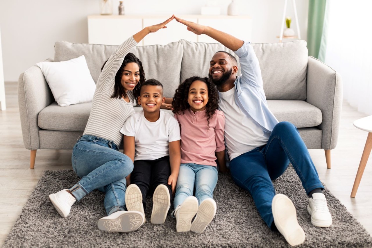 Black parents making symbolic roof of hands above their children.