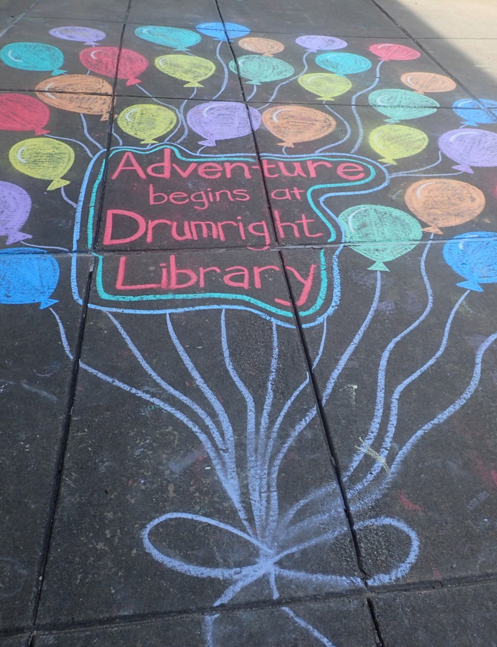 SIdewalk Chalk Art - text says Adventure Begins at Drumright Library