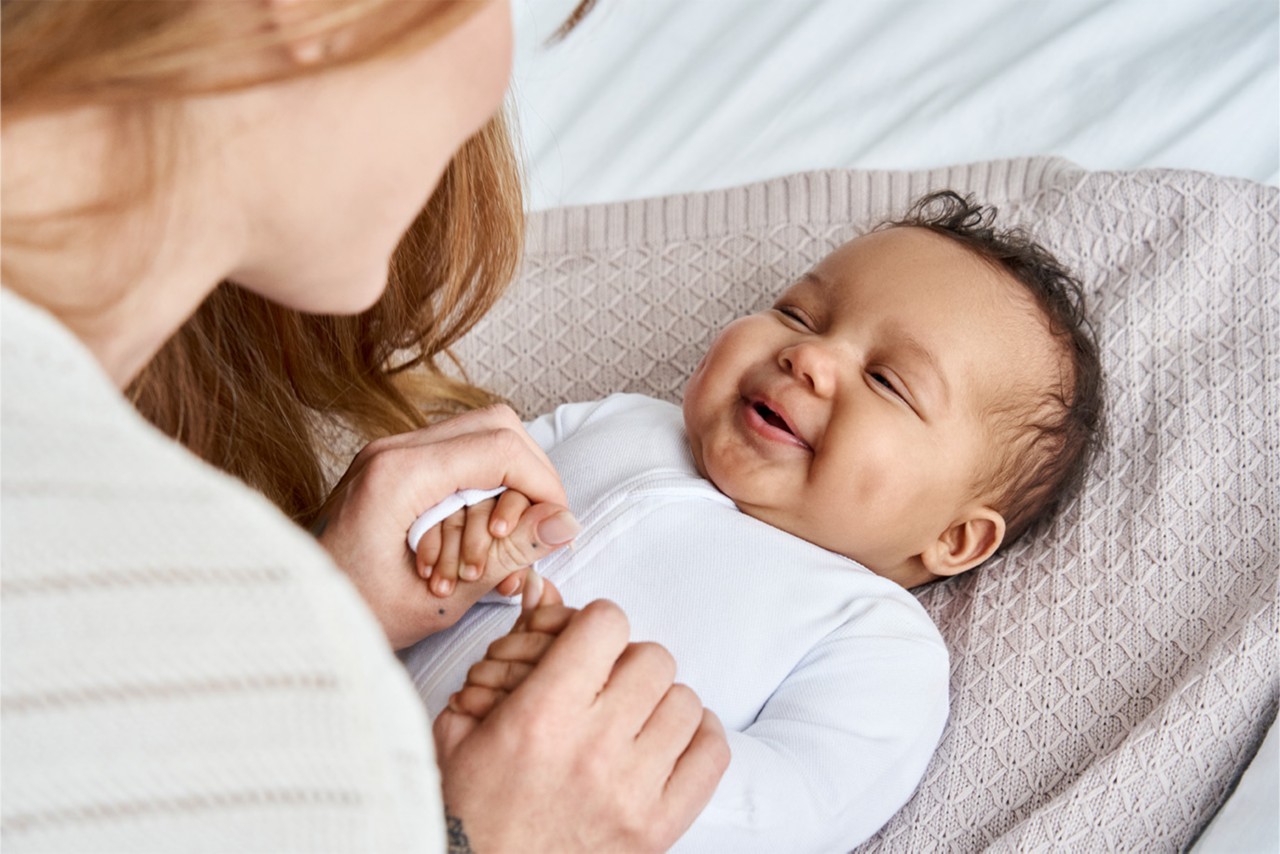 A baby smiles while laying down. 