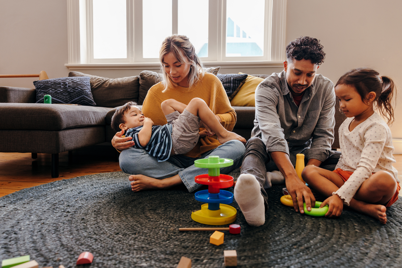 Mom and dad playing with their kids in the living room at home. Two young parents having fun with their son and daughter during playtime. Family of four spending some quality time together.