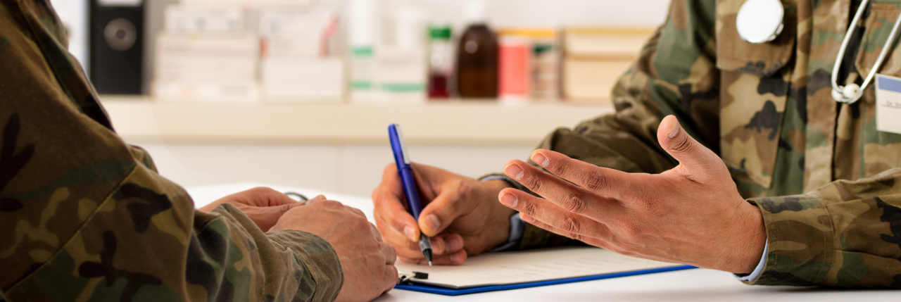 Military nurse filling out a form in front of military patient.