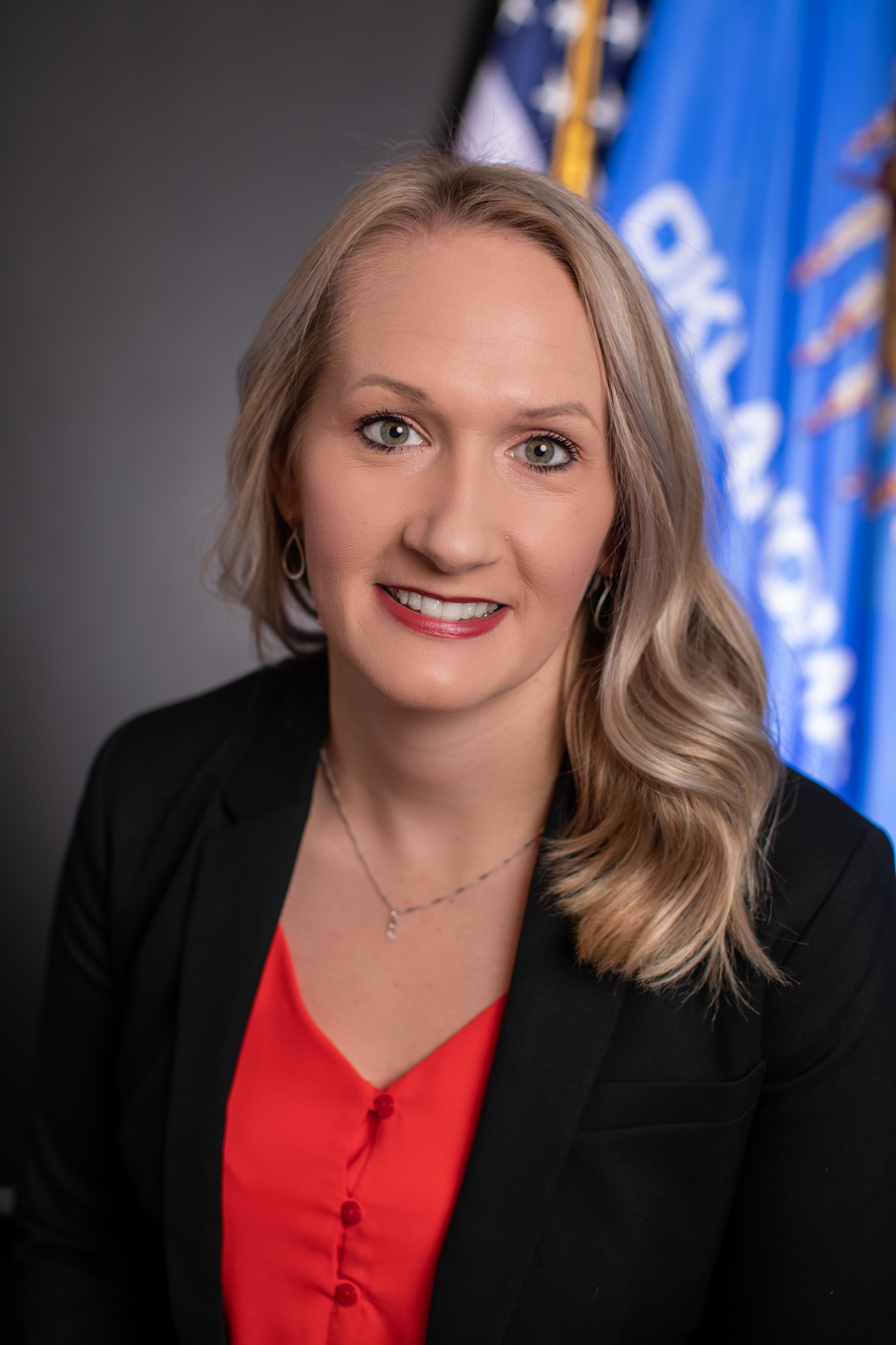 Headshot of Erica ONeal in front of US and Oklahoma flags