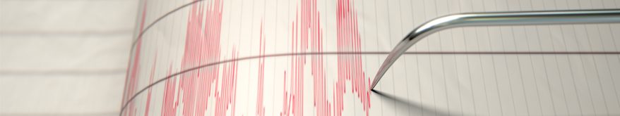 A metal needle creates red lines on white paper representing a seismograph that detects earthquake activity