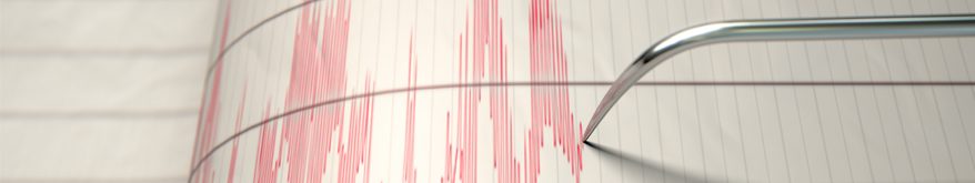 A metal needle creates red lines on white paper representing a seismograph that detects earthquake activity
