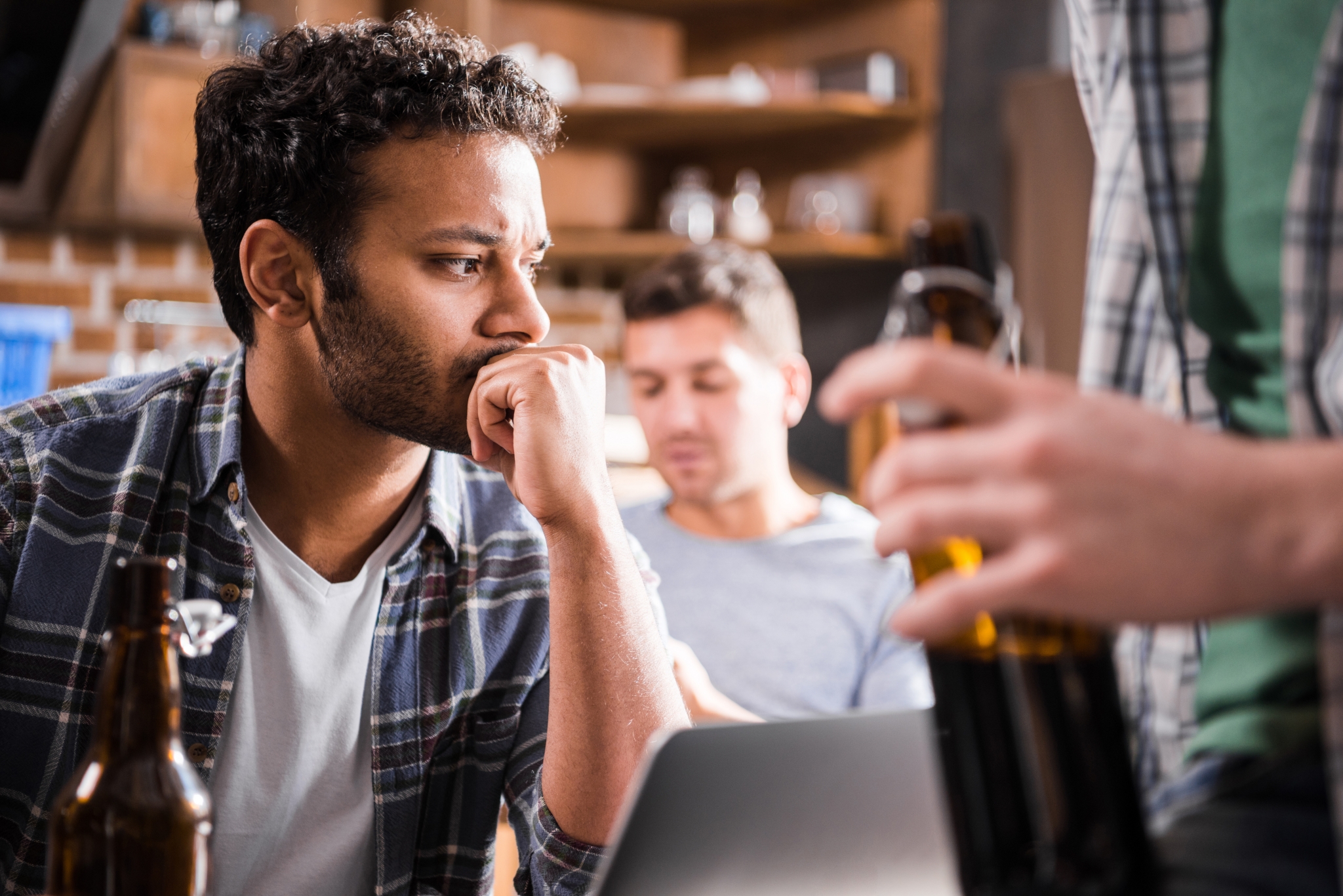 Serious young man using laptop while young people having fun with beer Serious young man using laptop while young people having fun with beer