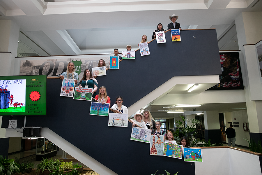winners of the 2019 poster contest holding their winning posters while standing on the steps inside the transportation building