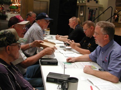 A group of men help the public program their NOAA radios. 