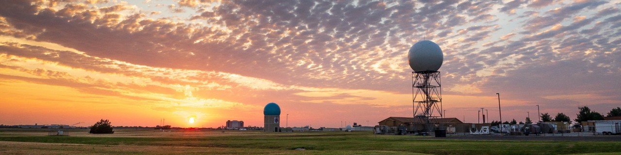 Sunset red sky with lots of clouds over pasture land with a house.