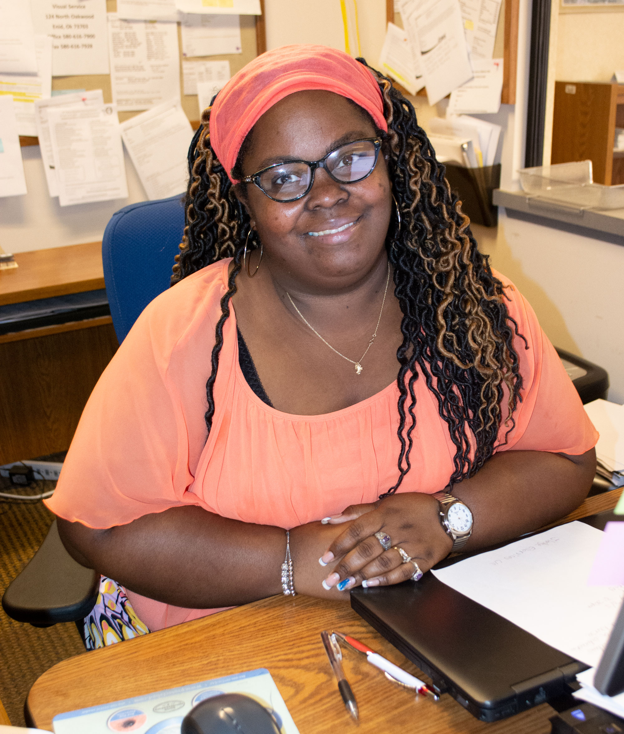A woman sitting at her desk smiles for the camera.