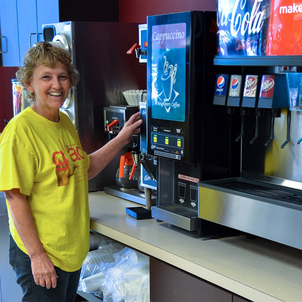 a woman stands in from of soda fountain machine