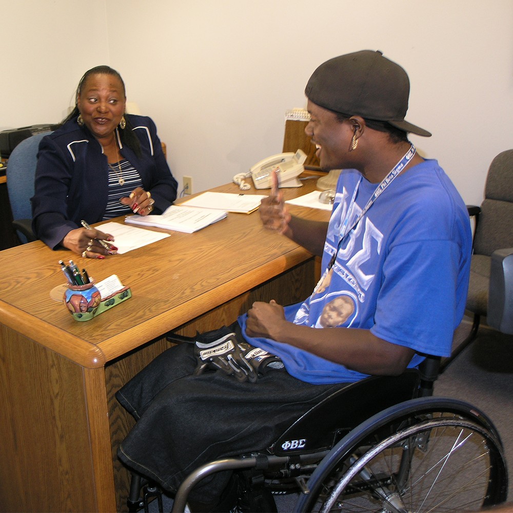 An female counselor talks with young man in wheelchair.
