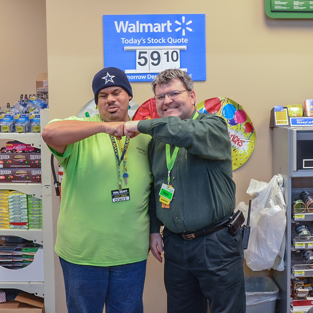 A Walmart manager and an employee with disabilities fist pump for the camera.