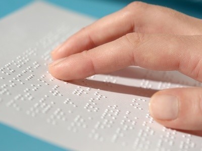 Fingers read braille on page.